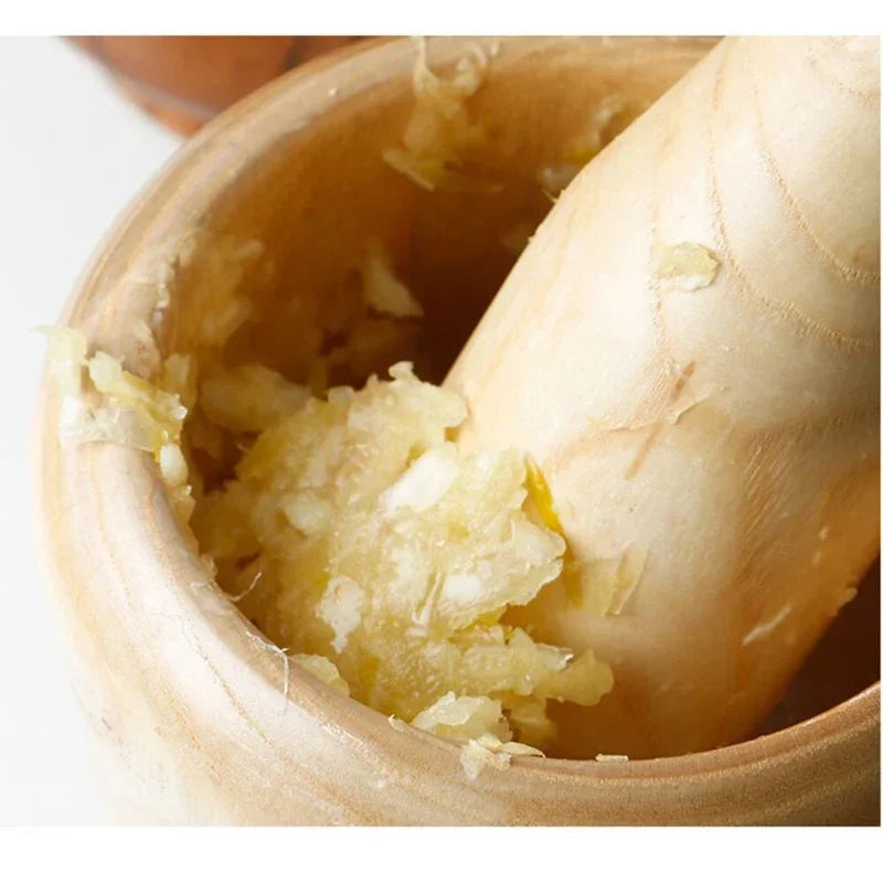 Wooden masher with mashed garlic in a wooden container