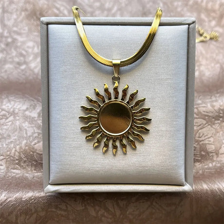 Gold sun-shaped pendant on a gold chain in a jewelry box.
