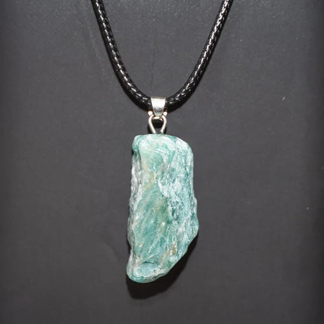 Turquoise stone pendant on a black cord against a dark background