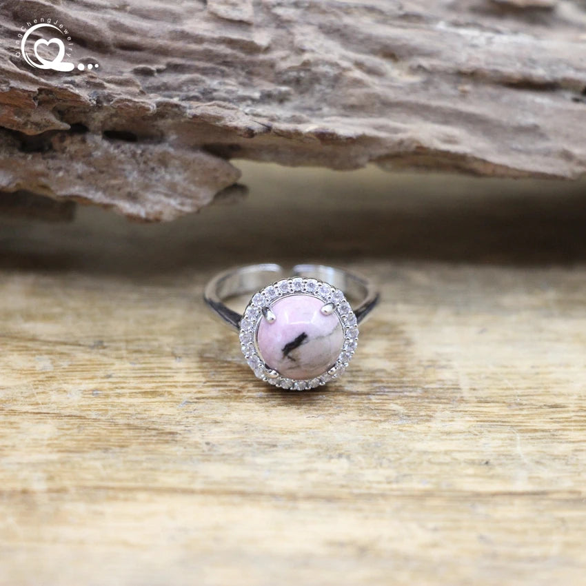 Silver ring with a pink stone on a wooden surface