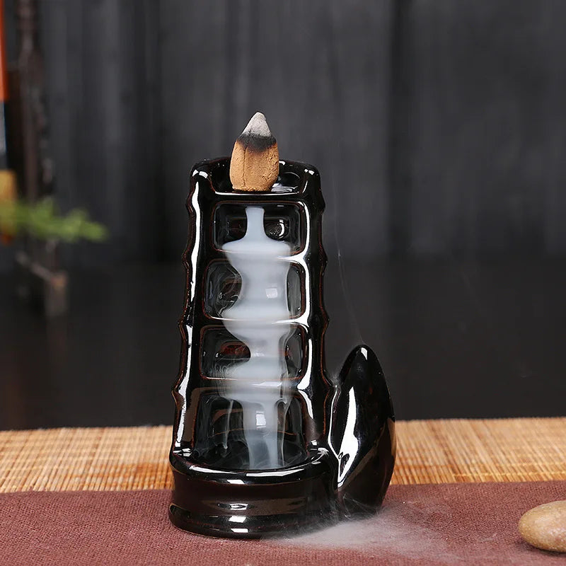 Black ceramic incense burner with smoke on a dark background