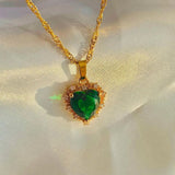 Gold necklace with a green heart-shaped pendant on a light background