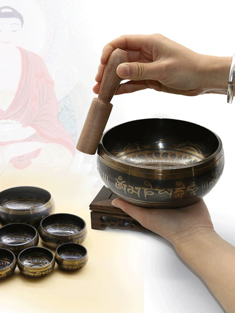 Person holding a singing bowl with a wooden striker on a white background