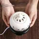 Person holding a white ceramic diffuser with floral designs on a wooden surface