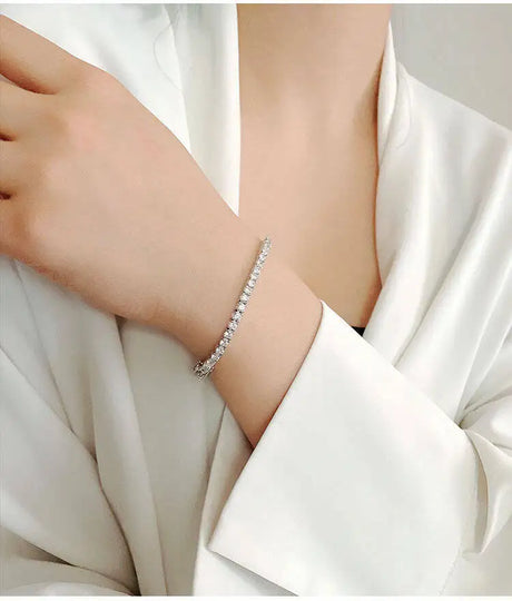 Silver bracelet on a person's wrist with a white fabric background