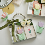 Tulip-shaped candles in a box with decorative ribbons on a white surface