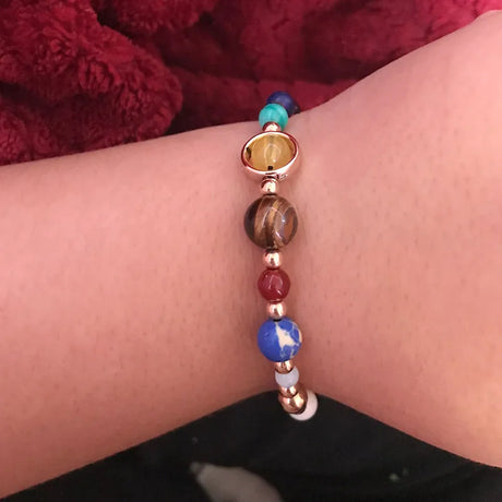 Close-up of a wrist wearing a colorful beaded bracelet against a red fabric background