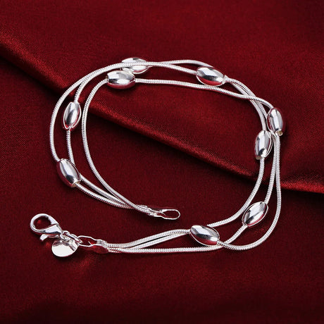 Silver bracelet with bead-like ends on a red fabric background
