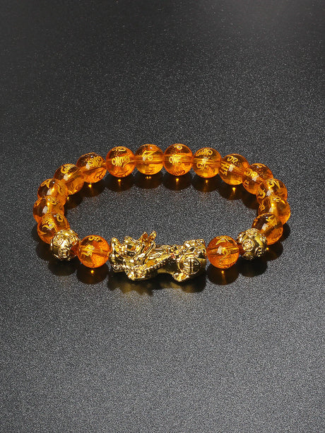 Bracelet with orange beads and gold accents on a dark background