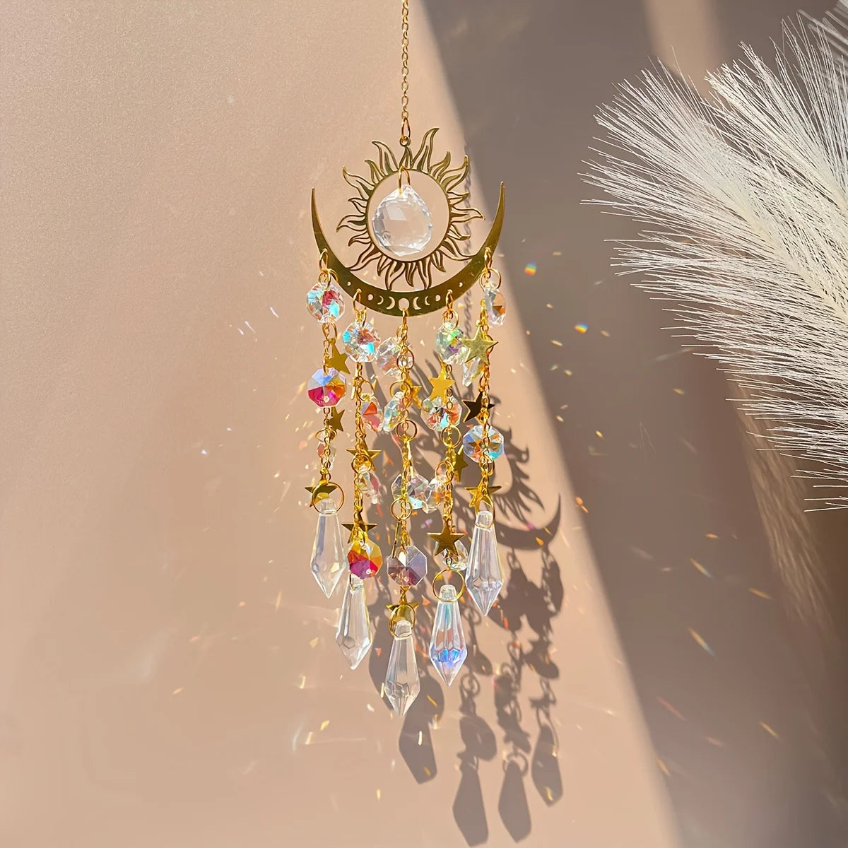Decorative hanging ornament with crystals and sun design on a neutral background