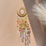 Decorative hanging ornament with crystals and sun design on a neutral background