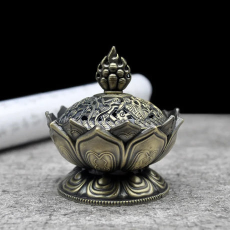Decorative bronze incense burner on a gray surface with a black background