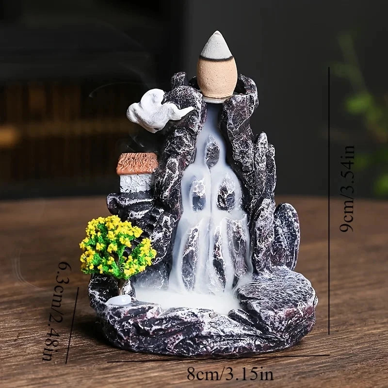Decorative mountain with waterfall and incense burner on a wooden surface
