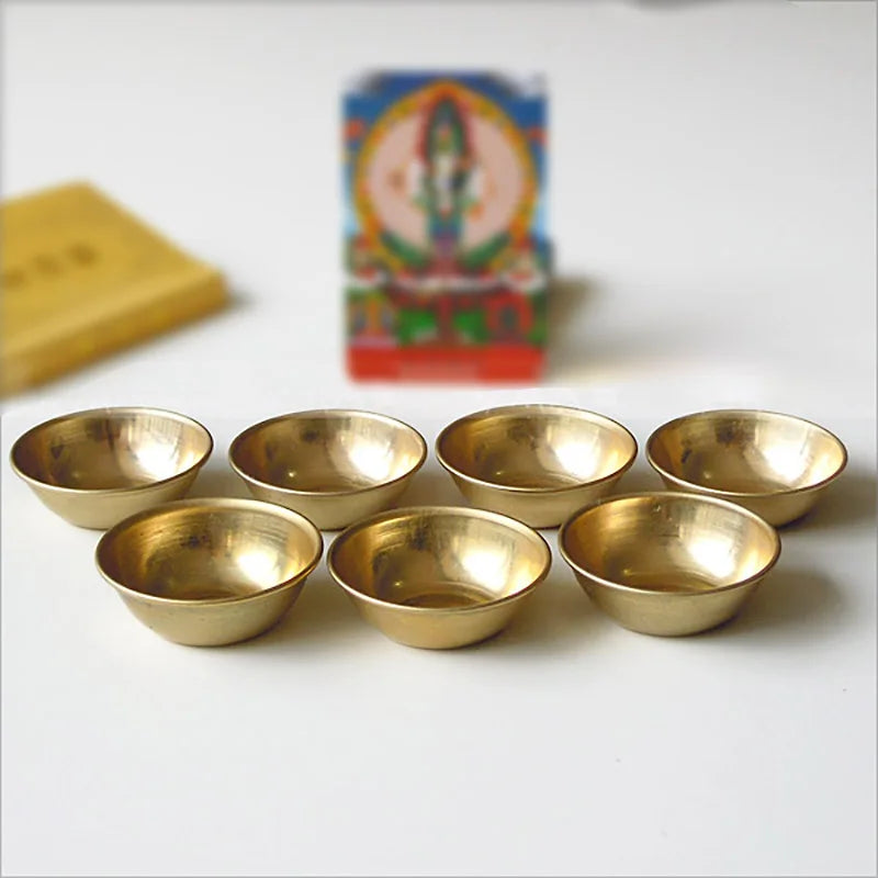 Set of gold bowls on a white surface with a colorful box in the background.