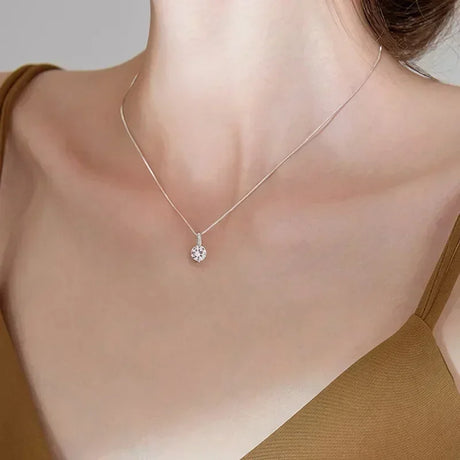 Silver necklace with a small pendant on a plain background