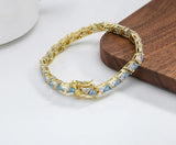 Gold bracelet with blue stones on a wooden block, branded 'Orsa Jewels'.