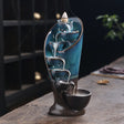 Decorative water fountain with blue liquid and a candle on a wooden surface.