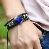 Bracelet with a zodiac sign charm on a wrist against a blurred green background
