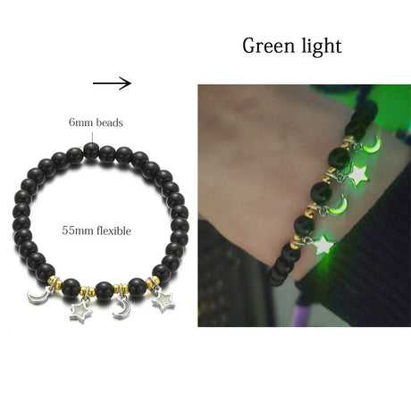 Black beaded bracelet with star and moon charms, showing green glow in dark setting.