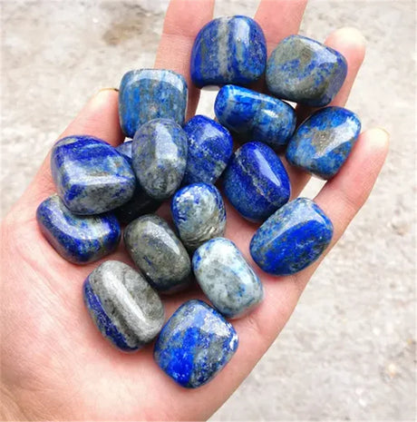 Hand holding a collection of blue and gray stones on a neutral background
