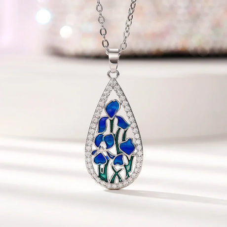 Teardrop-shaped pendant with blue floral design on a white background