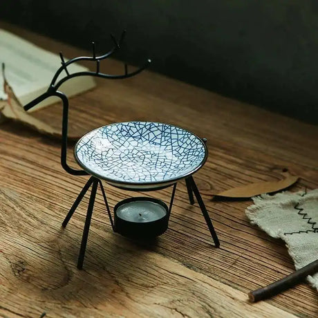 Decorative candle holder with cracked ceramic dish on a wooden surface