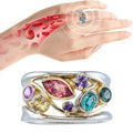 Multicolored gemstone ring on a hand with a close-up of skin texture.