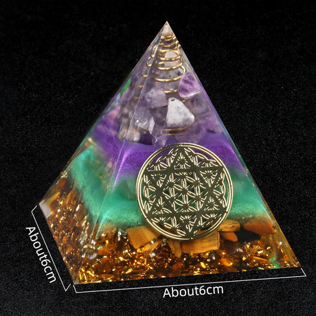 Pyramid-shaped crystal orgone with gold emblem on a black background
