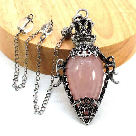 Pink pendant with silver chain on a wooden surface