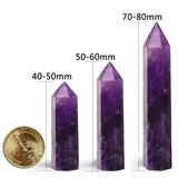 Three purple crystal points with measurements and a gold coin for scale on a white background