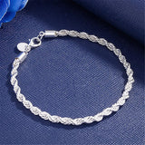 Silver braided bracelet on a blue fabric background