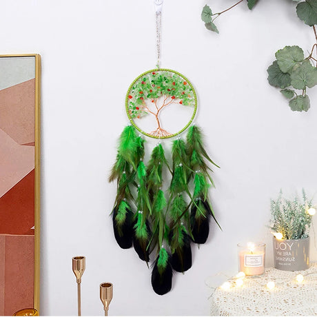 Green and black feathered dreamcatcher hanging on a white wall with decorative elements.