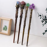 Four decorative sticks with gemstone tops on a white surface.