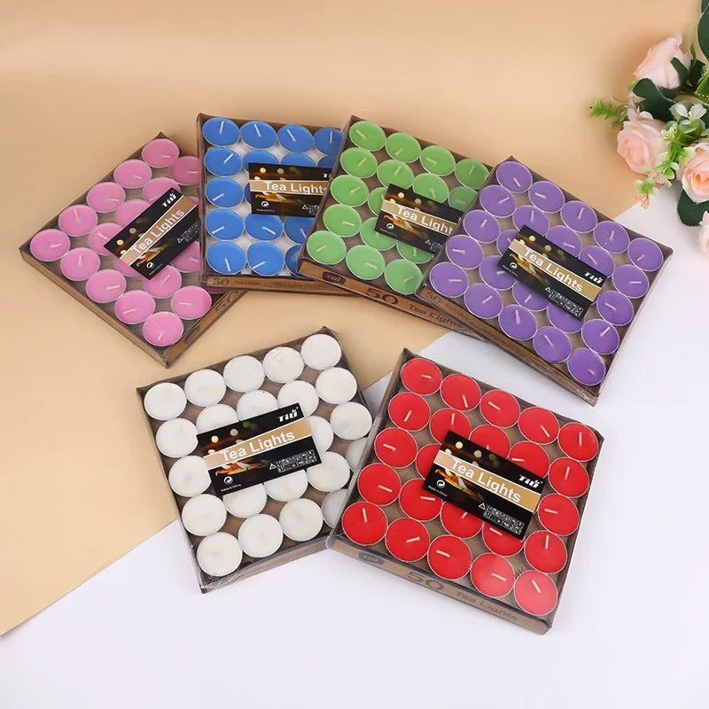 Assorted colored tea light candles in their packaging on a beige and white background.