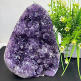 Amethyst crystal formation with green plants in the background
