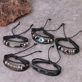 Set of black leather bracelets with various charms on a gray surface