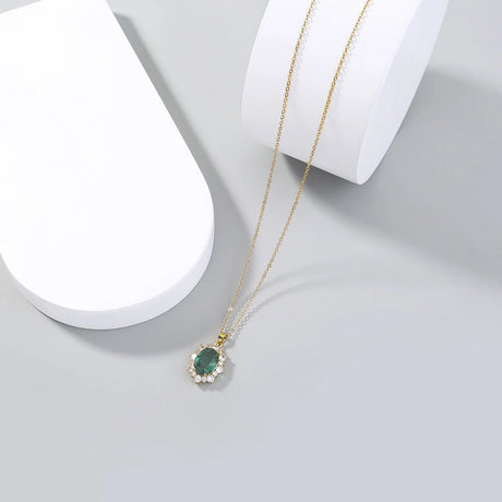 Gold necklace with a green gemstone pendant on a white surface