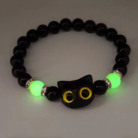 Glowing black beaded bracelet with cat-shaped charm on a white background