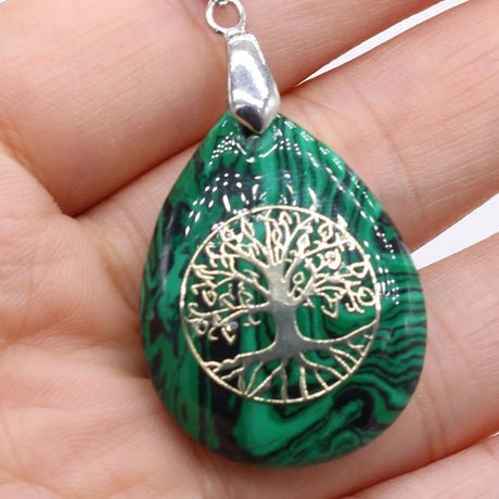 Green marbled pendant with gold tree of life design held in a hand