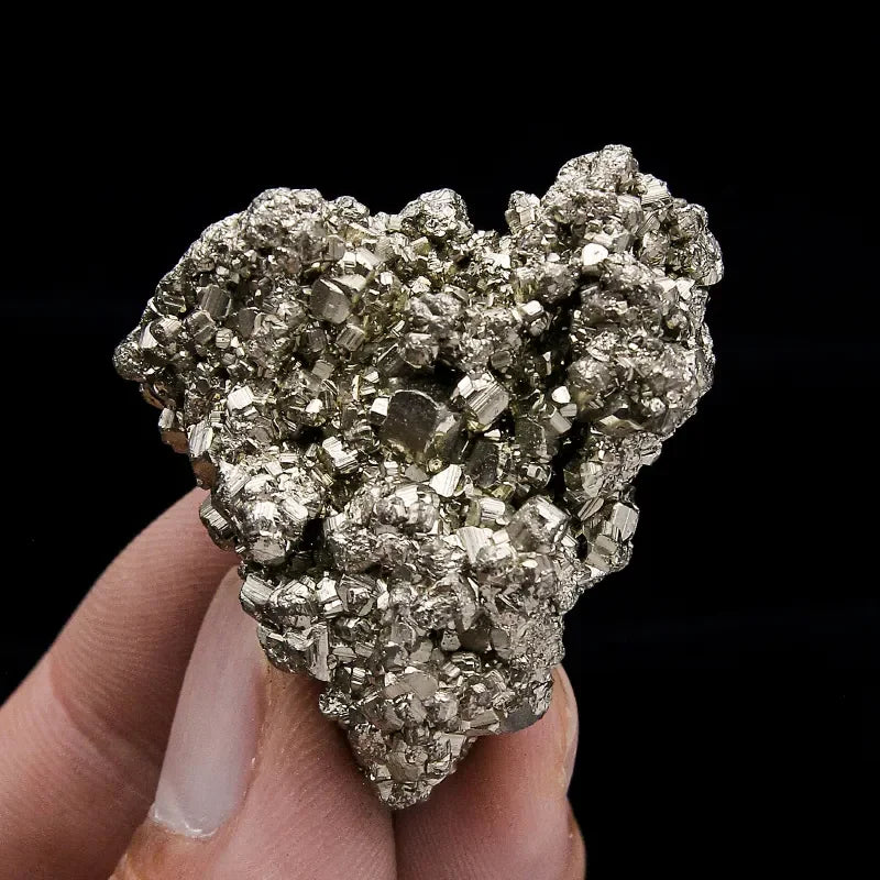 Mineral sample held in a hand against a black background