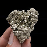 Mineral sample held in a hand against a black background