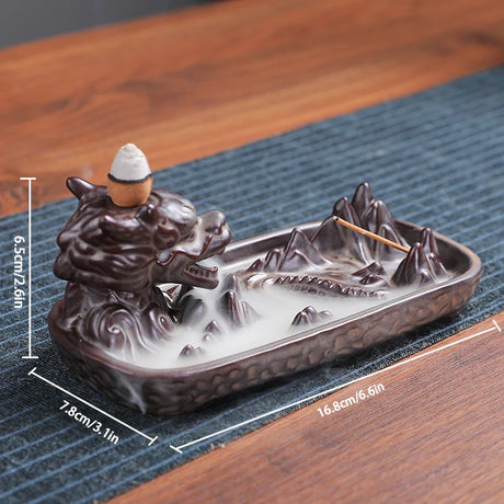 Ceramic incense burner with mountain and boat design on a wooden surface