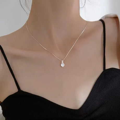 Necklace with a pendant on a mannequin wearing a black top against a neutral background