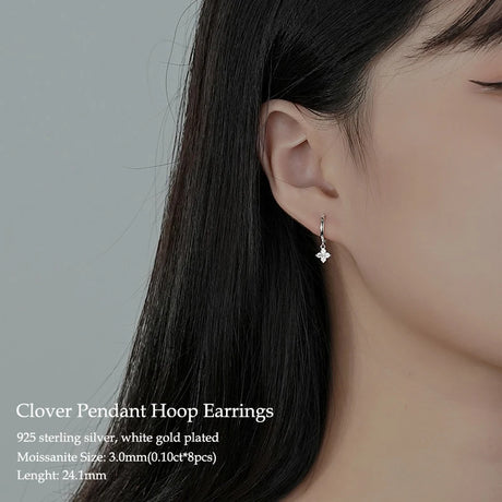 Clover pendant hoop earrings on an ear with product details.