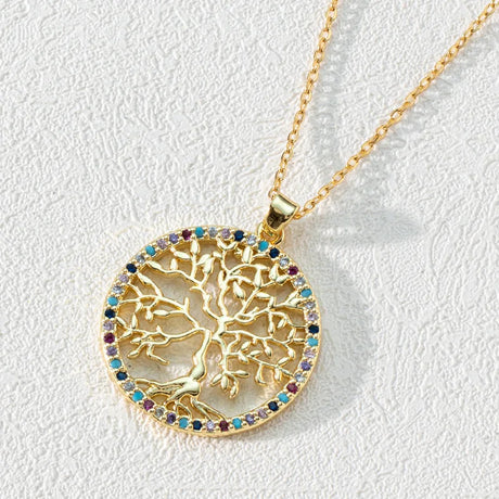 Gold necklace with a tree of life pendant on a light gray background