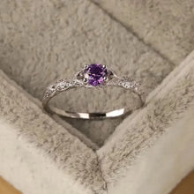 Silver ring with a purple gemstone in a textured box