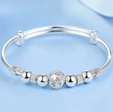 Silver bracelet with decorative beads on a light blue background