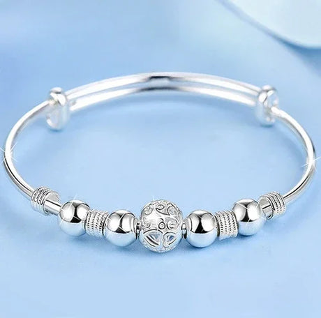 Silver bracelet with decorative beads on a light blue background