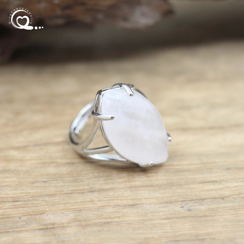 Silver ring with a large white stone on a wooden surface