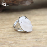 Silver ring with a large white stone on a wooden surface
